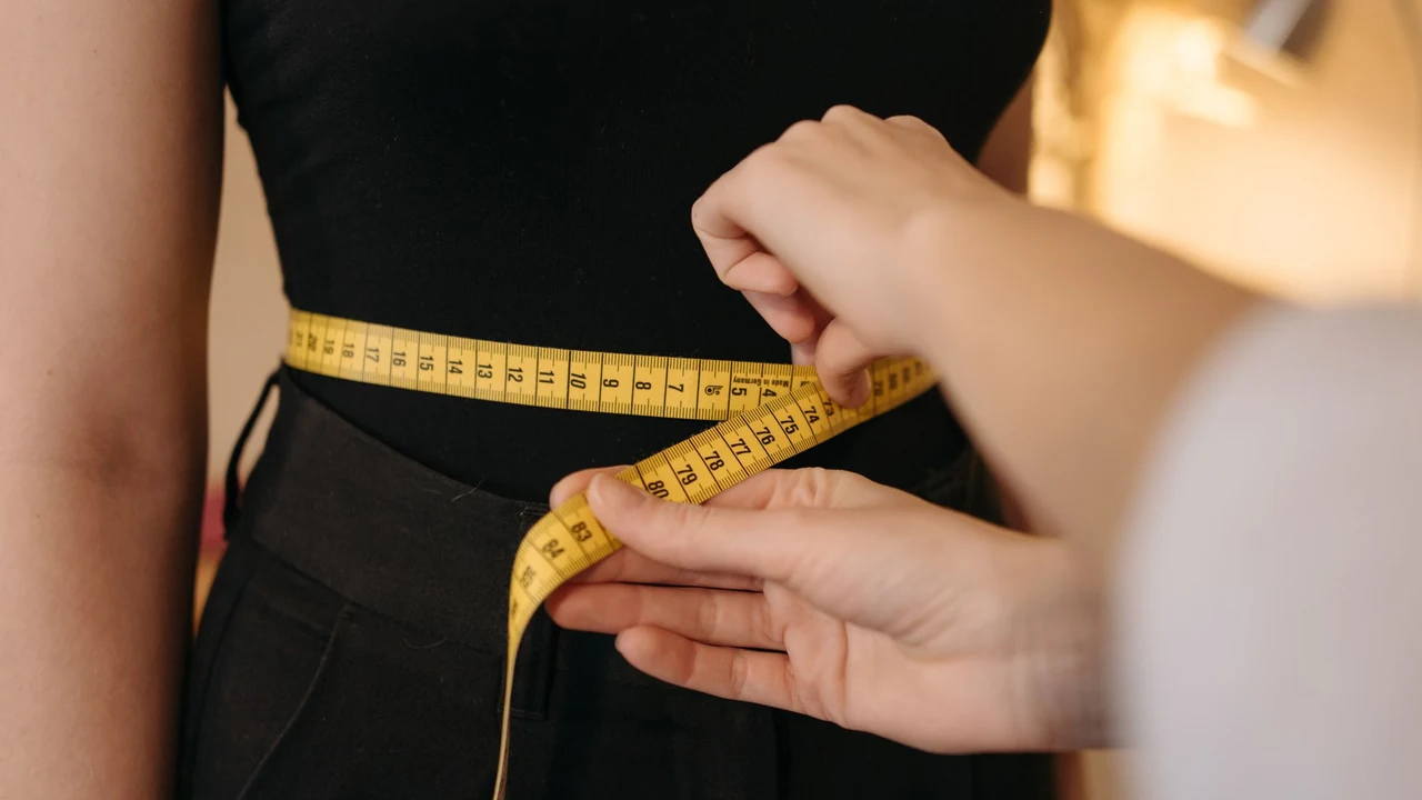 Hands positioning a measuring tape around an adult waist