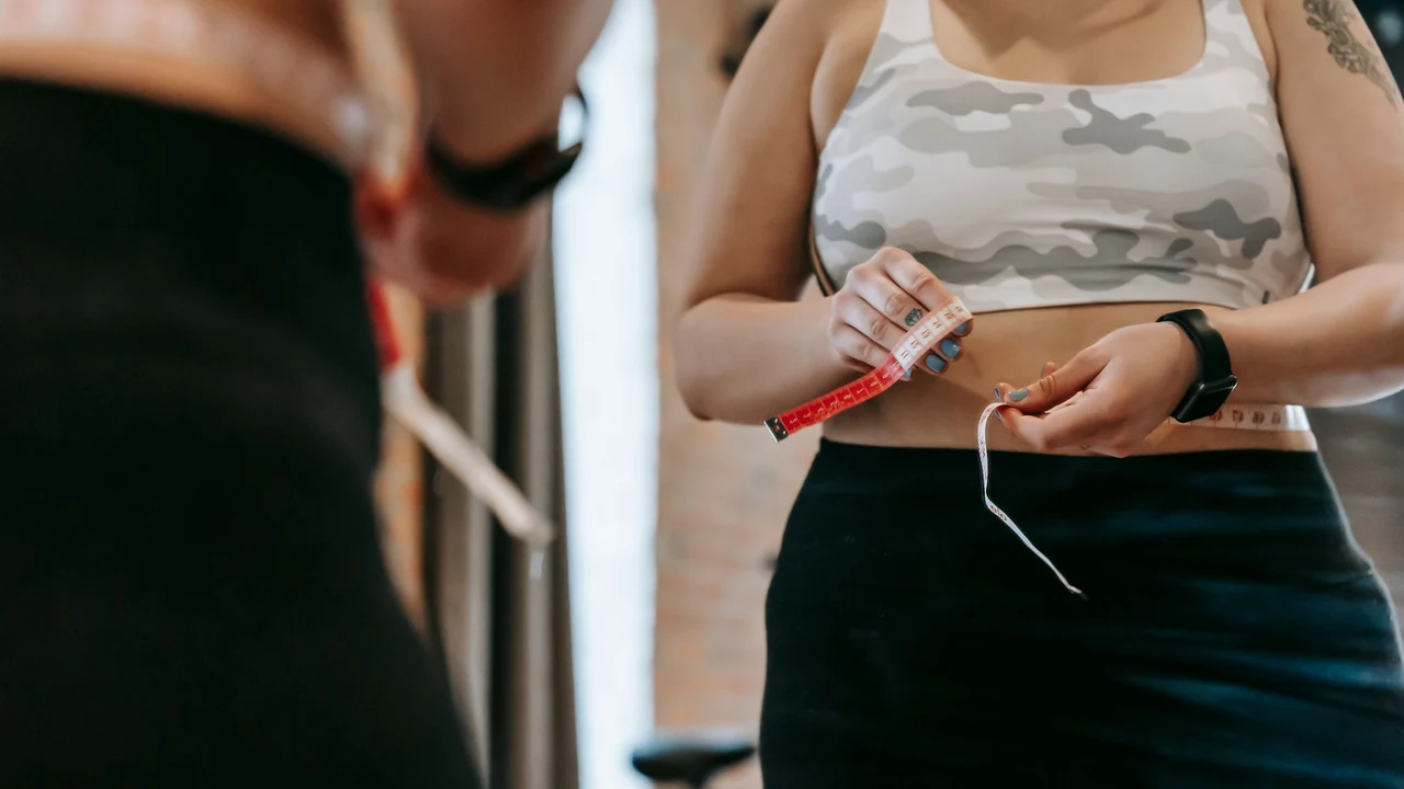 An adult holding a measuring tape beside a mirror