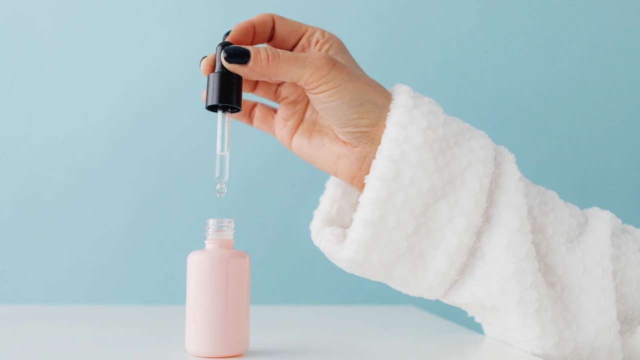 Hand holding a cosmetic dropper above a bottle