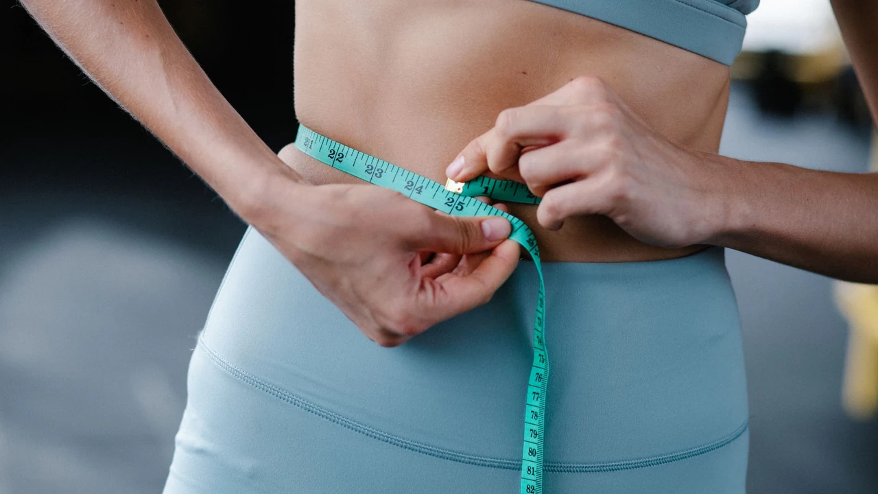 Hands measuring a waist with a tape measure