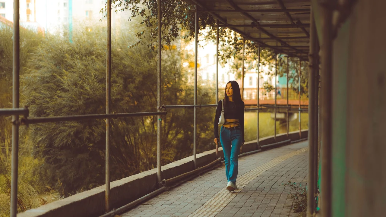Woman walking beside a glass building
