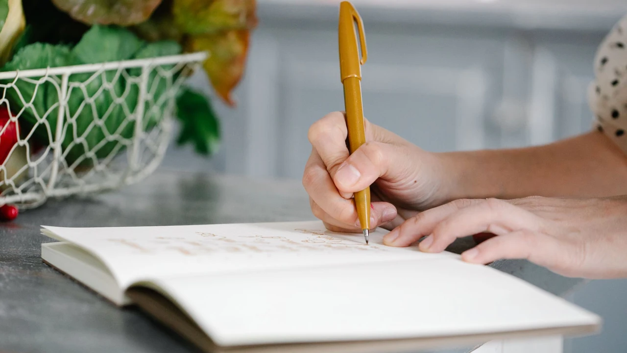 Hands writing notes at a kitchen table