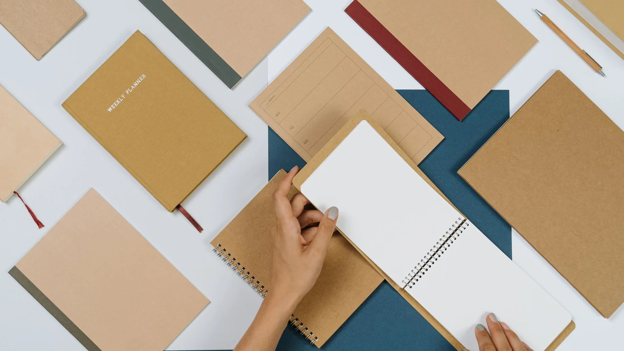 Hands holding a blank notebook on a desk