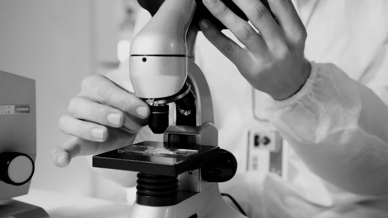 A researcher looking through a laboratory microscope.