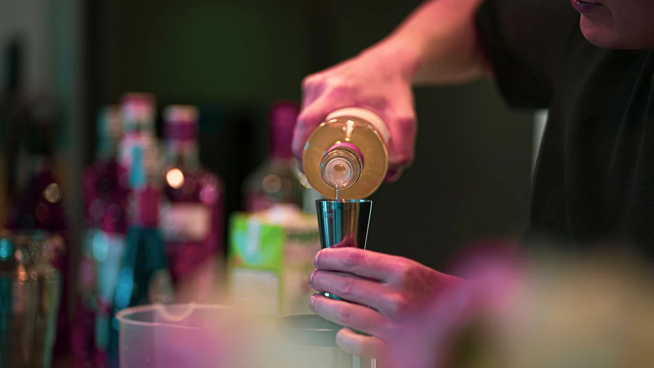 A bartender measuring a drink during preparation.