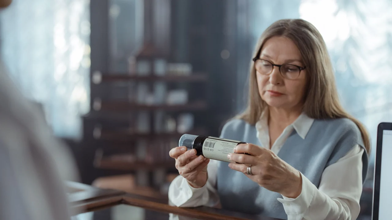 A person examining the label on a medicine container.