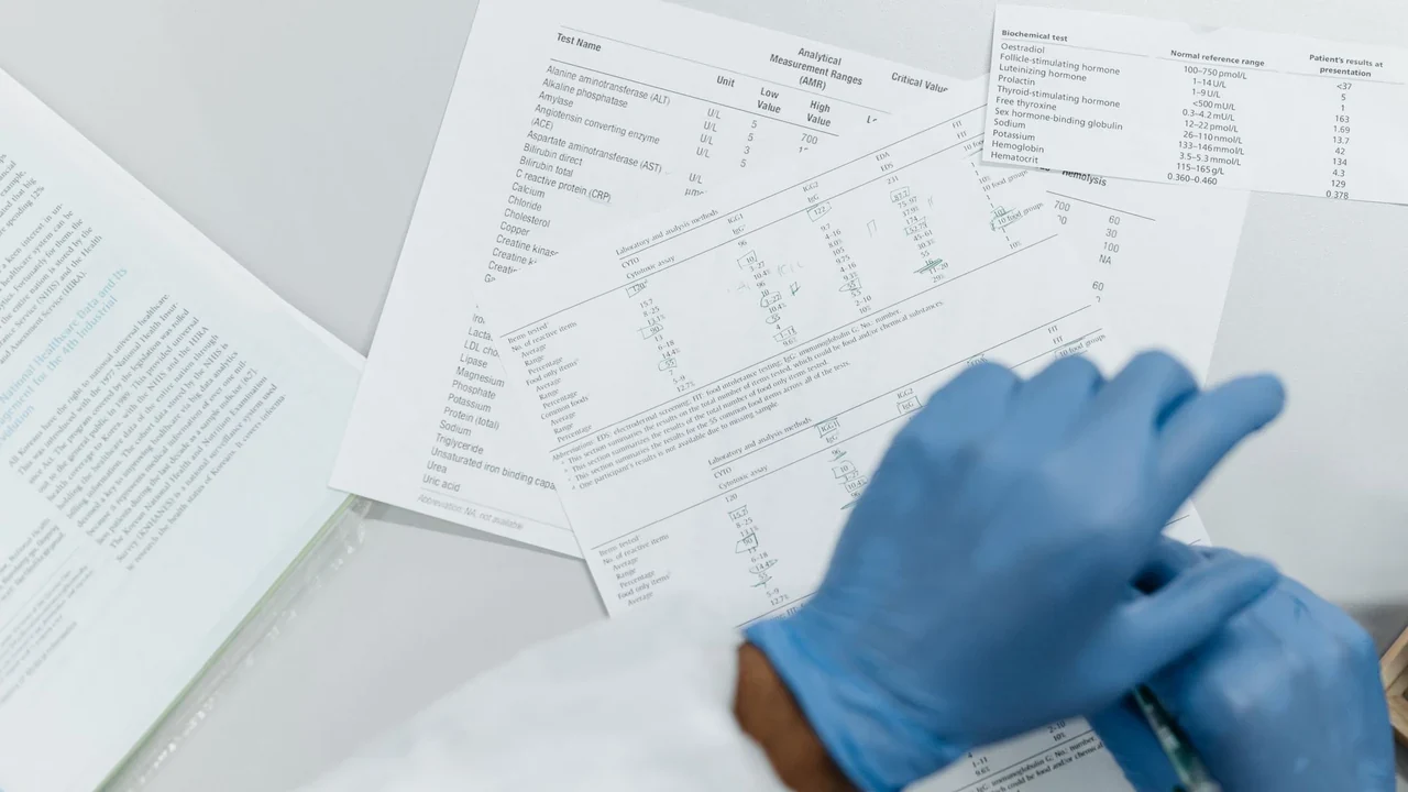 Gloved hands resting beside printed laboratory reports.