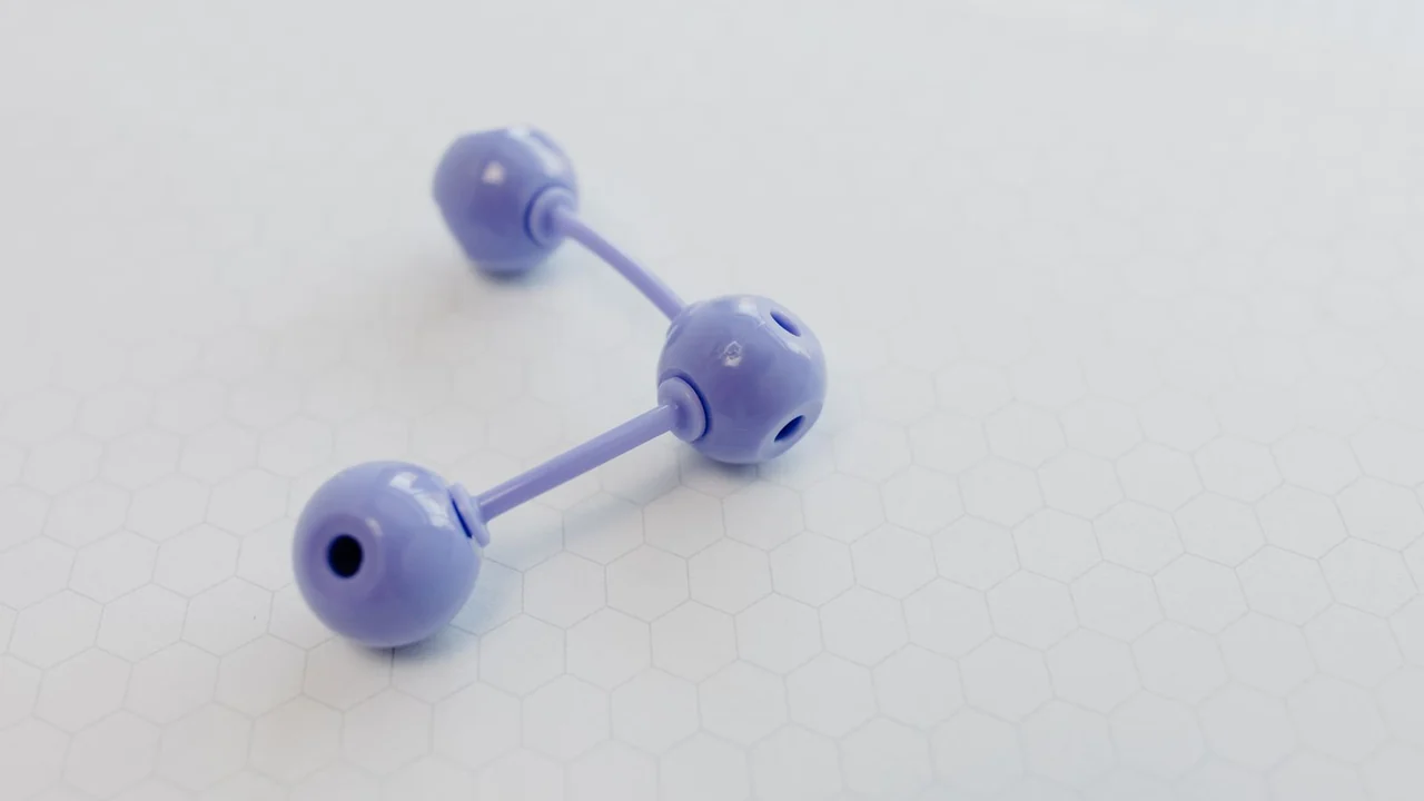 A small purple ball-and-stick model on graph paper