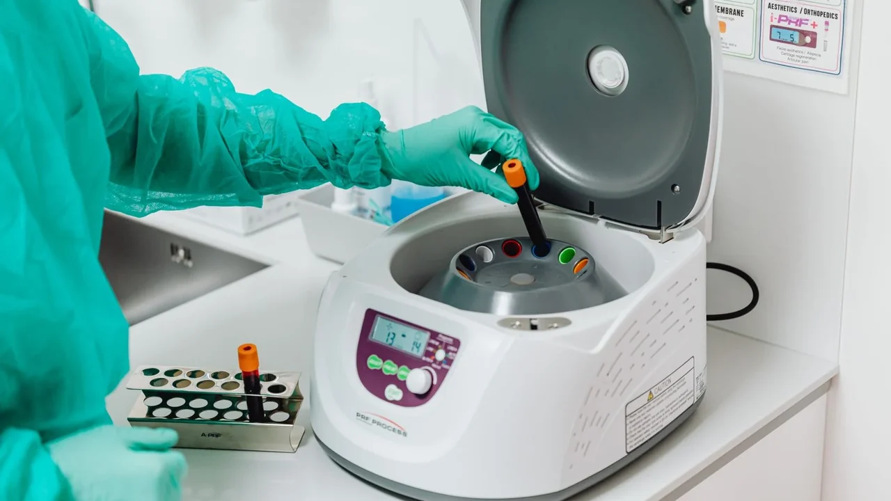 Gloved hands placing a sample tube in a centrifuge