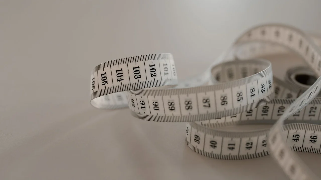 A white measuring tape loosely curled on a pale surface