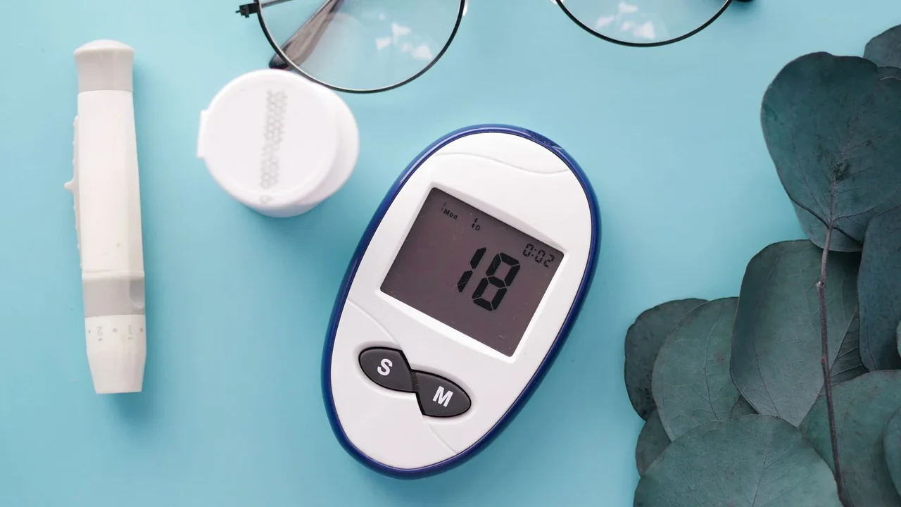 Glucose meter and test supplies on a blue surface