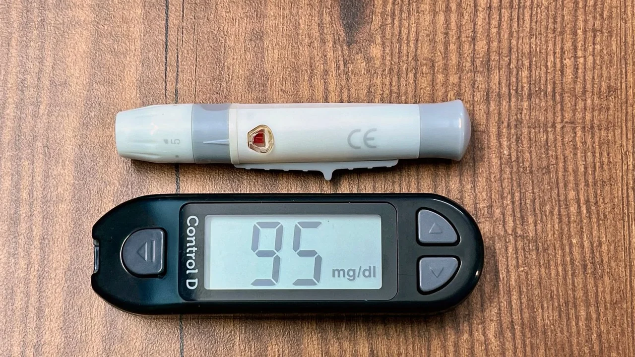 A glucose meter and lancing device on a wooden surface