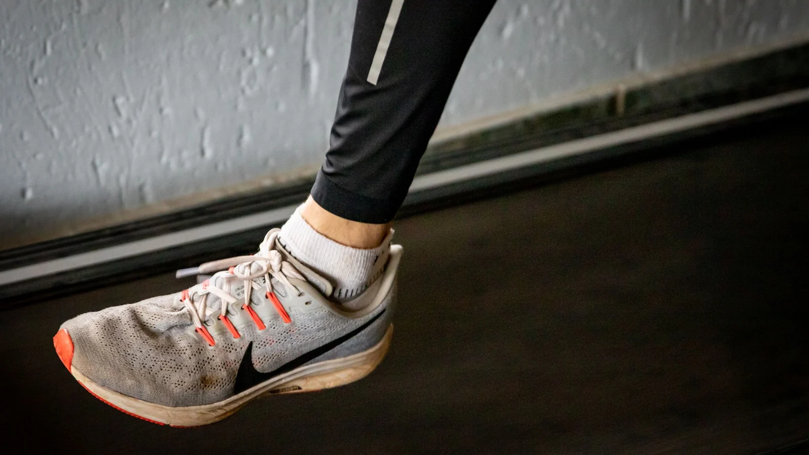 A detailed view of a sneaker mid-stride on a treadmill, showcasing active lifestyle footwear.