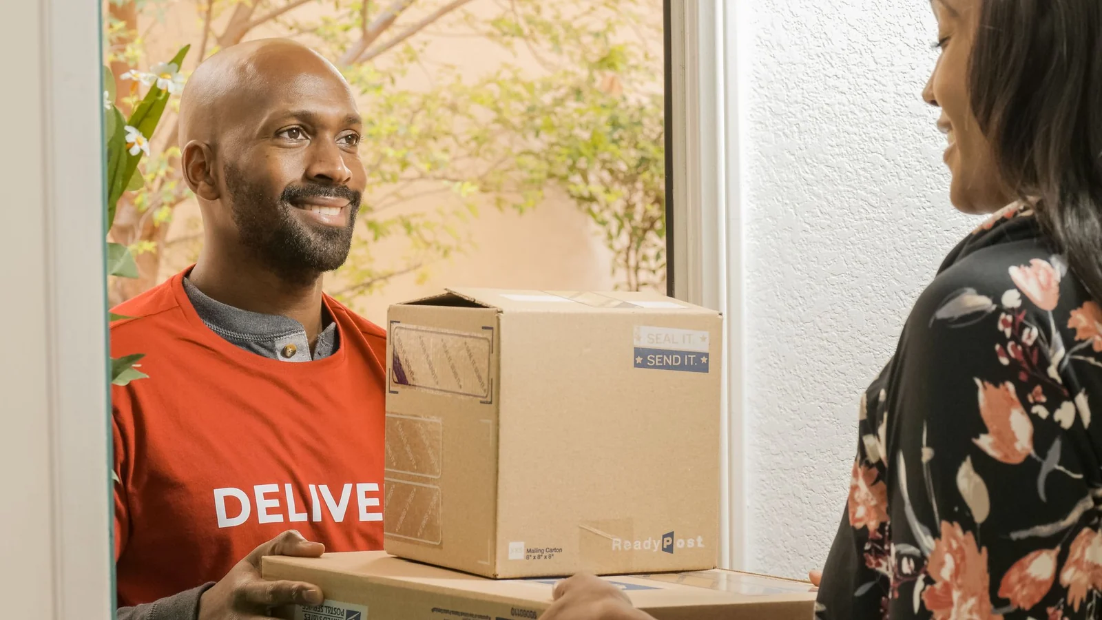 A parcel handed to a recipient at a doorway; illustrative stock photograph.