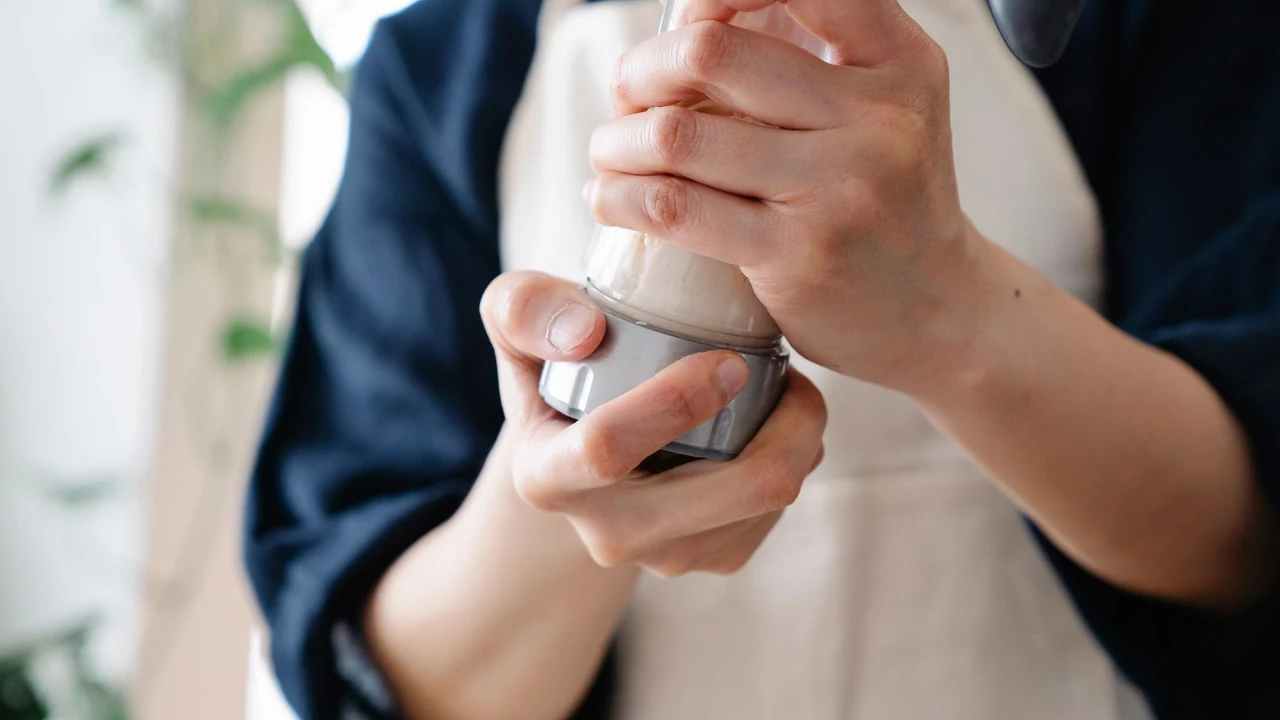 Hands holding a cylindrical container with a pale mixture inside