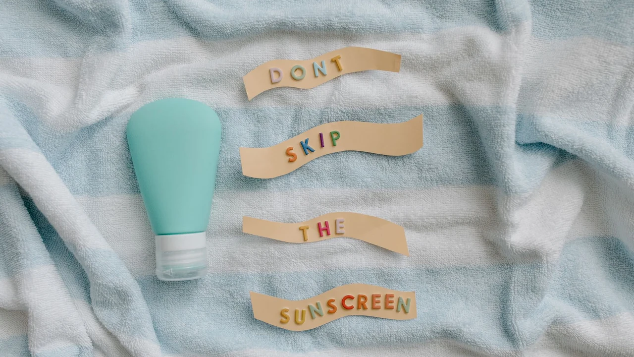 Two sunscreen tubes on a towel beside a reminder to use sunscreen