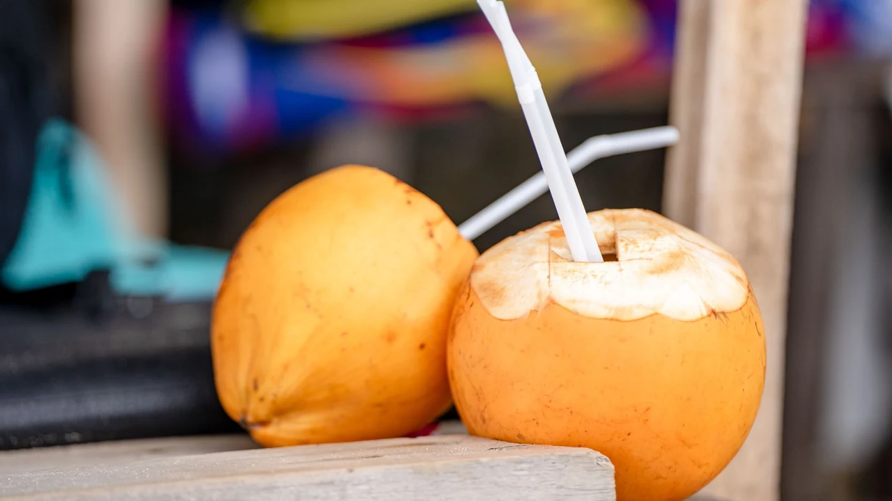 Opened coconut with a drinking straw.