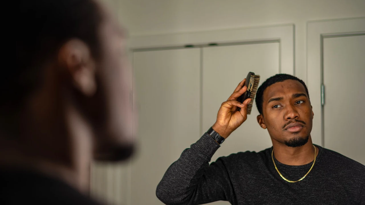 Man combing his hair while looking in a mirror.