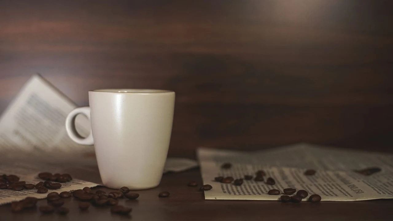 White coffee cup and coffee beans on a wooden table.