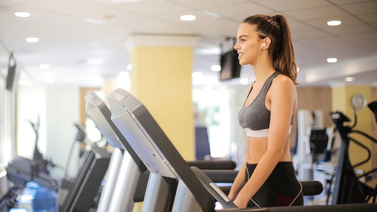 Woman standing on a treadmill in a gym.