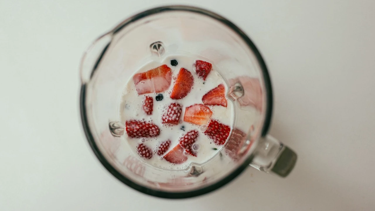 Overhead view of fruit and milk in a blender.