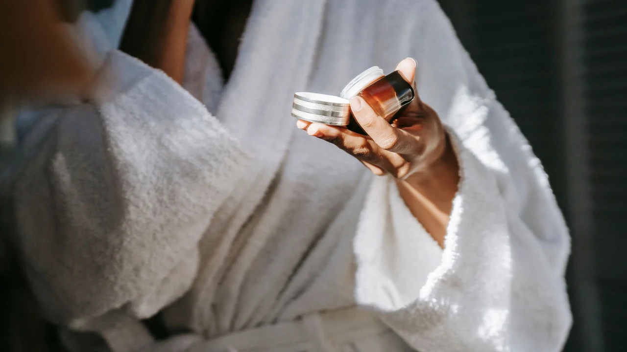 Hands holding an open jar of face cream.