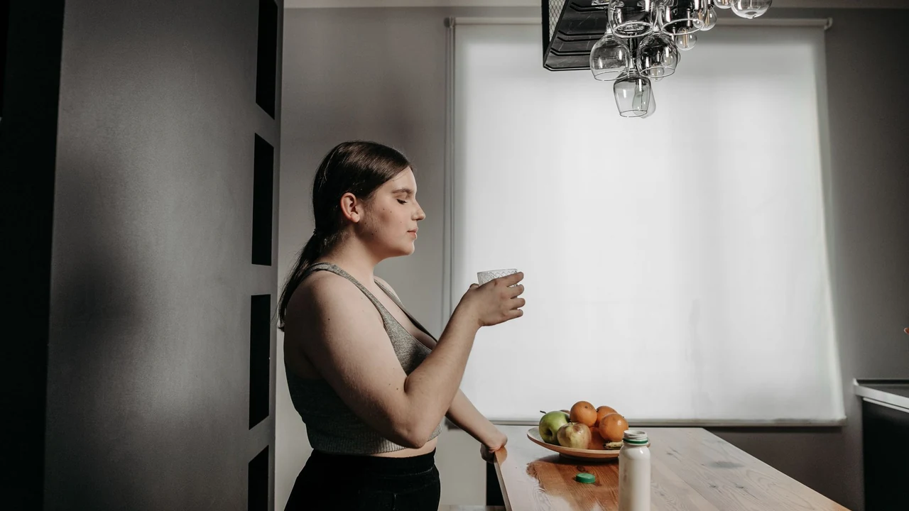 Woman holding a glass of water in a kitchen.