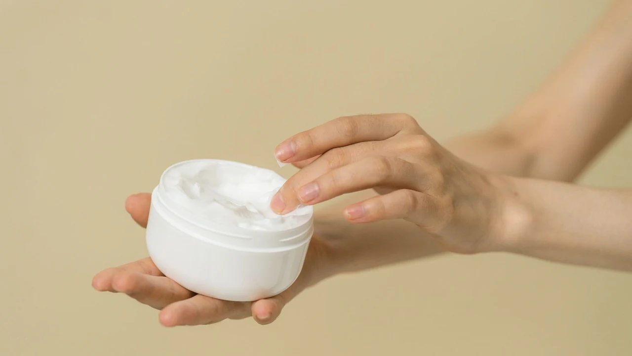 Hands beside an open jar of cream.