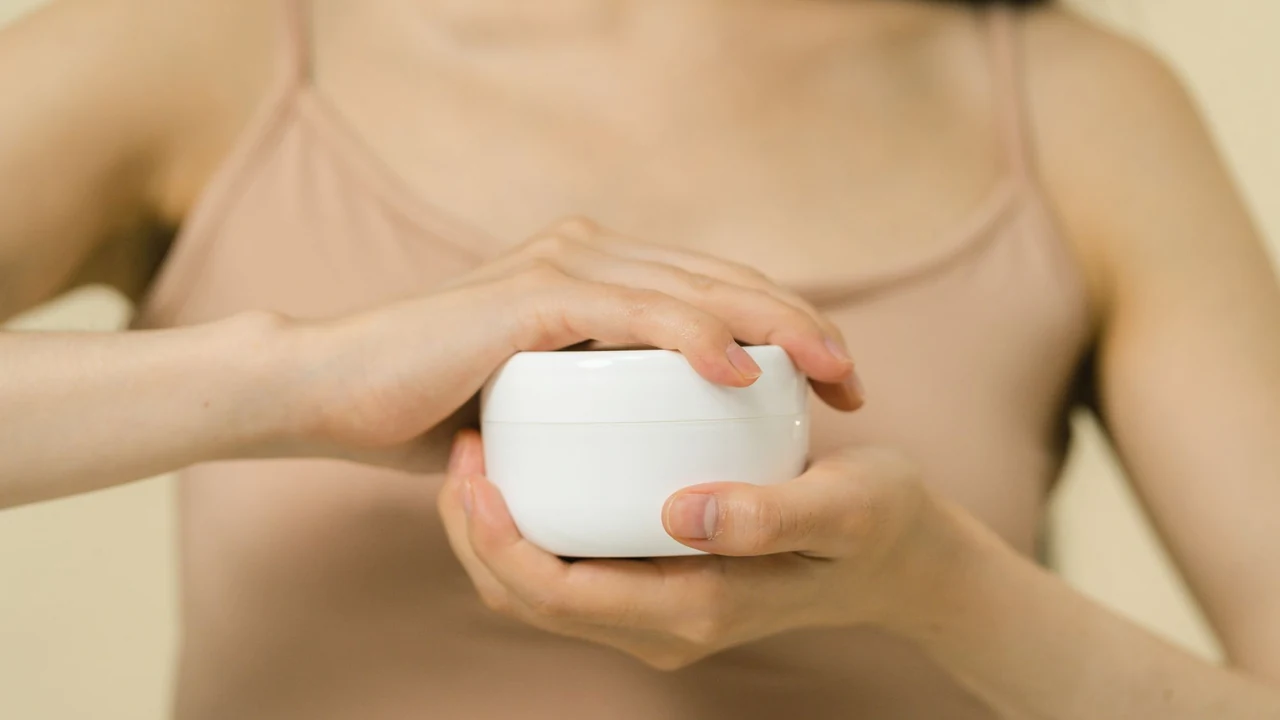 A person holding a plain white moisturiser jar