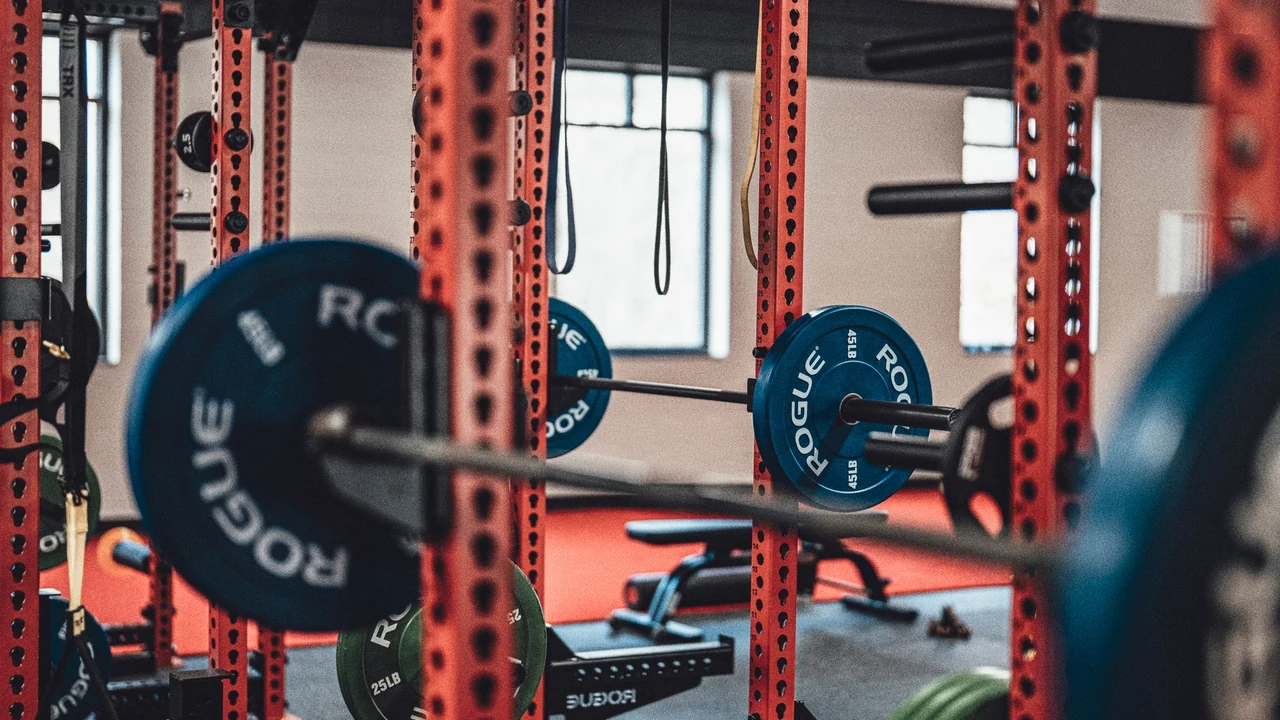 A barbell and plates inside a red squat rack