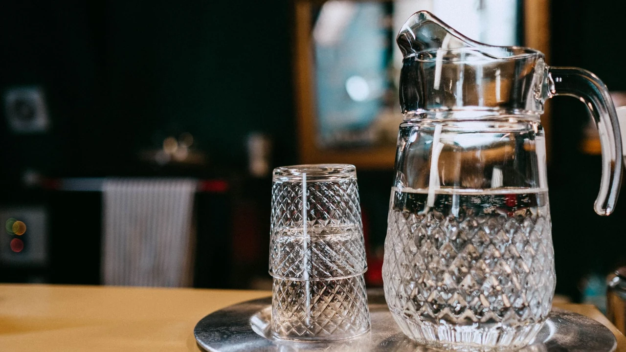 A glass jug and drinking glass on a wooden table